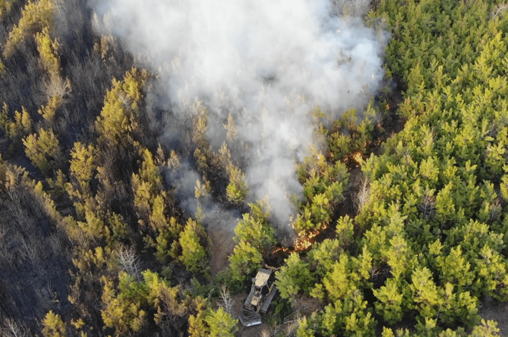 aerial photograph of wildfire with smoke and a dozer